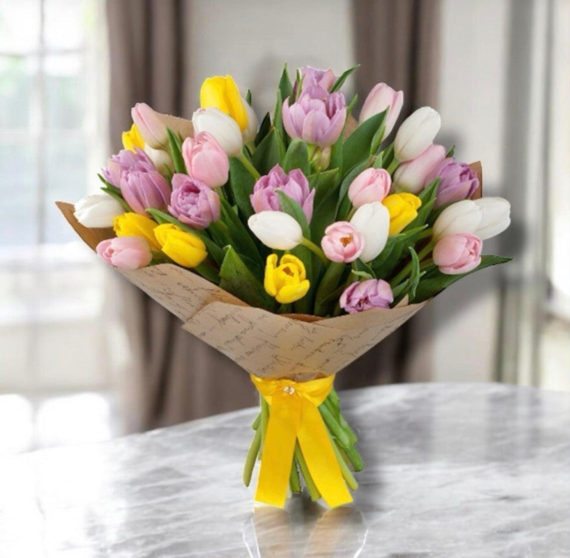 The Daily Bloom featuring mixed tulips in yellow, pink, lavender, and white wrapped in kraft paper with a yellow ribbon